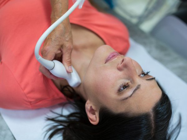 Woman getting ultrasound of a thyroid from doctor in hospital